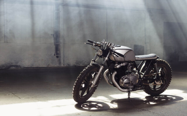 motorcycle-standing-in-dark-building-in-rays-of-su-PGGG49F