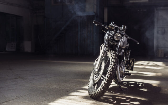 Vintage motorcycle standing in a dark building in the rays of sunlight. Toned colors. Front view