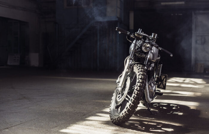 Vintage motorcycle standing in a dark building in the rays of sunlight. Toned colors. Front view